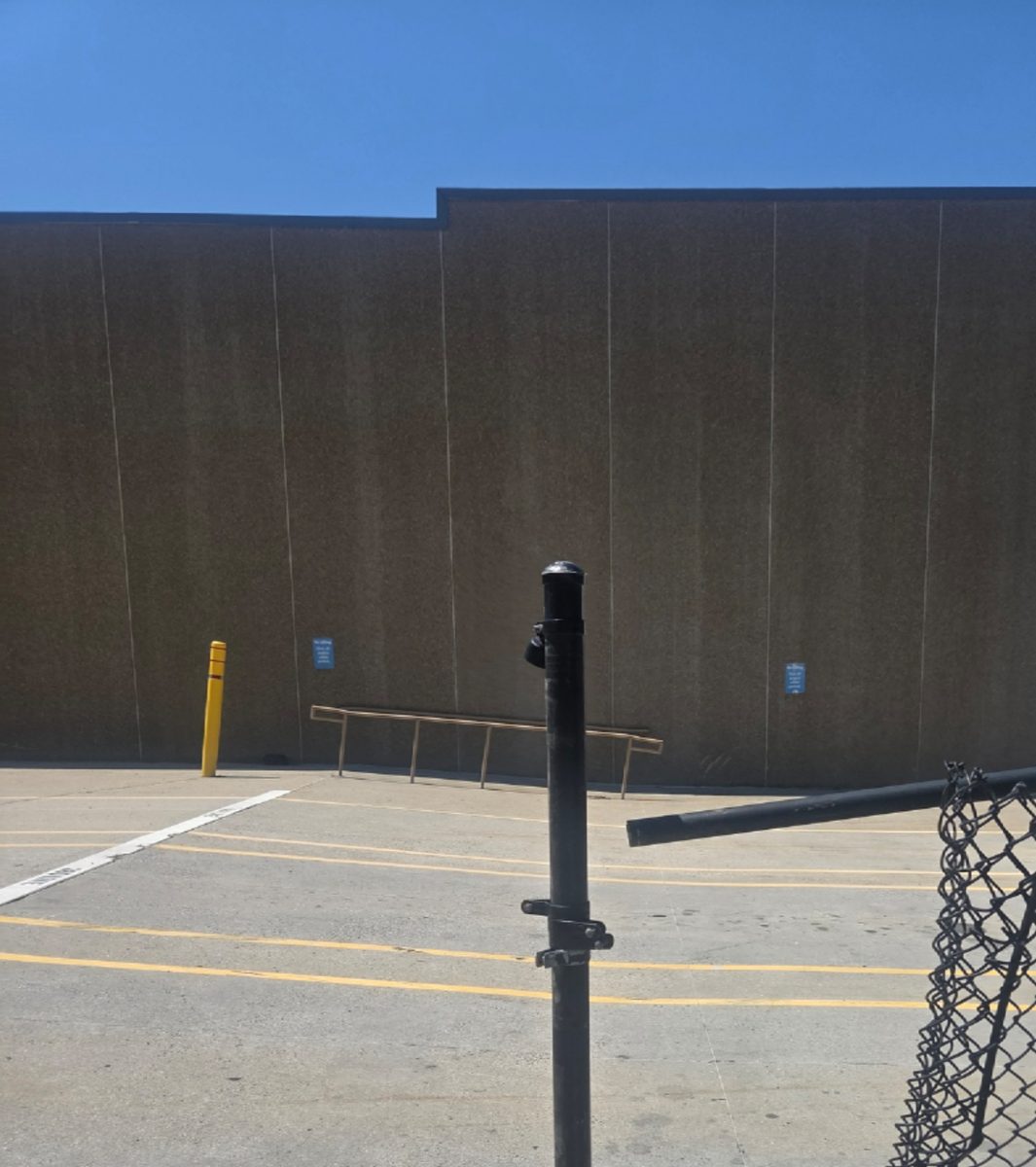 Before: Damaged chain-link gate behind a commercial building, with the gate panel bent and off its post